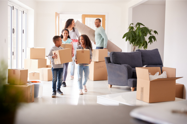 Family of five entering home with moving boxes - three children and mom and dad